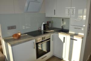 cocina con armarios blancos y encimera en Meerblick FeWo Nr A-107 en Sierksdorf