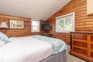a bedroom with wooden walls and a bed and a tv at The Cedarwood Inn & Suites in Sidney