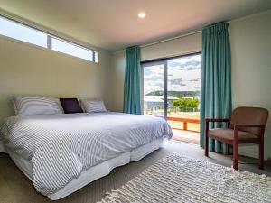a bedroom with a bed and a window and a chair at Alpine Retreat - Ohakune Holiday Home in Ohakune +13 photos