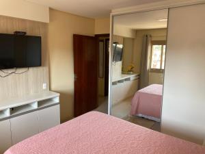 1 dormitorio con cama rosa y espejo en Apartamento Maria Helena, en Torres