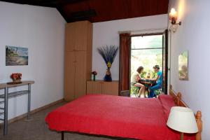 a bedroom with a red bed and two people sitting at a table at Residence San Damiano - Location Appartements, Studios & Chambres in Algajola