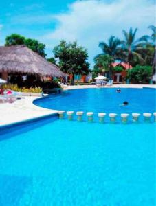 a large blue swimming pool with chairs and palm trees at Casa Brisa sol in Acapulco