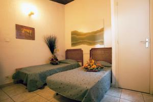 a room with two beds and a table with flowers on it at Residence San Damiano - Location Appartements, Studios & Chambres in Algajola +16 photos