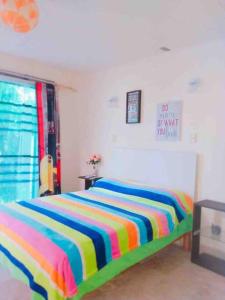 a bedroom with a colorful striped bed in a room at Casa Brisa sol in Acapulco +14 photos