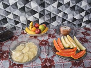 a table with plates of fruits and vegetables on it at Pousada Canto Juquehy in Juquei