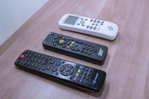 three remote controls sitting on top of a wooden table at Hotel Bandeirantes in Cachoeira do Campo