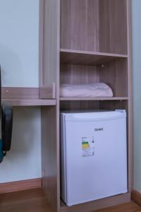 a refrigerator in a wooden cabinet next to a freezer at Hotel Bandeirantes in Cachoeira do Campo