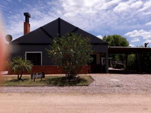 uma casa negra com uma árvore em frente em El CHANFLE em Punta Del Diablo