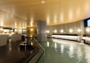 a swimming pool in a hotel lobby with a tub at APA Hotel & Resort Niigata Ekimae Odori in Niigata