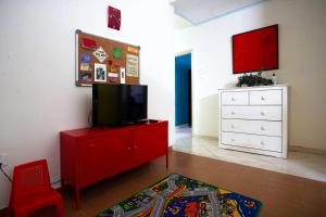 uma sala de estar com uma televisão num armário vermelho em Teratak As-Sakinah em Merlimau