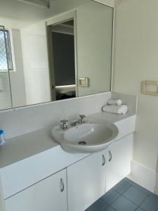 a white bathroom with a sink and a mirror at Bayview Harbourview Apartments in Mooloolaba