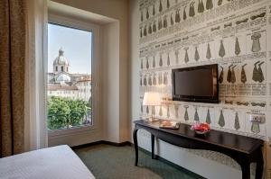 a bedroom with a window and a desk with a television at Palace Hotel Lake Como in Como