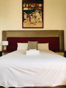 a bedroom with a white bed with a painting on the wall at Larq'a Park Rooms in Lima