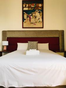 a bed with a white bedspread and a painting on the wall at Larq'a Park Rooms in Lima