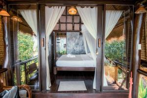 a bedroom with a bed in a room with windows at Baan Talay Koh Tao Resort & Yoga in Ko Tao