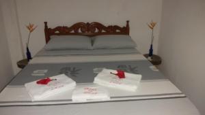 a bed with two white towels and red bows at Guest House Boki da Zezé in Marau