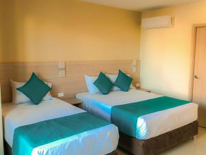 a bedroom with two beds with blue pillows at Balcones de la Quinta in Ríohacha