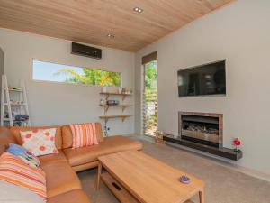 un soggiorno con divano e camino di Castaway Bach - Whangamata Holiday Home a Whangamata