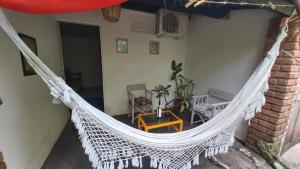 uma rede de descanso branca numa varanda com uma mesa e cadeiras em Guest House Boki da Zezé em Maraú