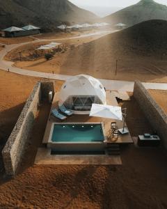 an outdoor pool with umbrellas and chairs in the desert at Mysk Moon Retreat in Sharjah