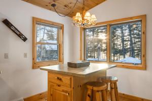 a kitchen with a island with two stools and two windows at Cabin on the Loop-Upper in Three Lakes