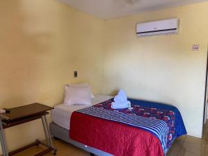 um pequeno quarto com uma cama com uma caixa azul em Hotel Real Alaska em Liberia
