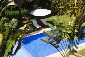 an overhead view of a swimming pool with a umbrella and chairs at Triplex vista mar no Pipa Beleza in Pipa