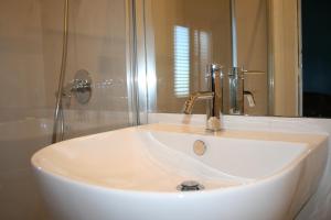 lavabo blanco en el baño con espejo en Villa Mara B&B, en Noto