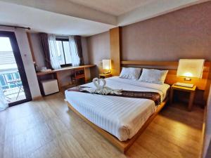 1 dormitorio con 1 cama grande con colcha blanca en Buritel Hotel en Buriram
