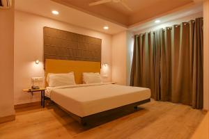 a bedroom with a large bed with a large headboard at FabHotel Suncitel Dum Dum Airport in Gauripur