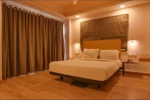 a bedroom with a large bed with a wooden headboard at FabHotel Suncitel Dum Dum Airport in Gauripur