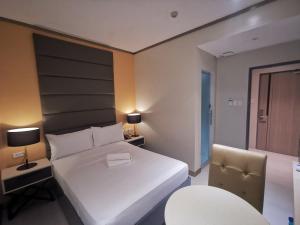ein Schlafzimmer mit einem großen weißen Bett und einem Stuhl in der Unterkunft Yes Hotel Pandi Bulacan in Pandi
