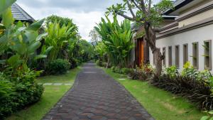 a path in a garden next to a house at The Grand Villandra Resort in Lovina