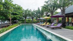 een zwembad met stoelen en parasols naast een huis bij The Grand Villandra Resort in Lovina