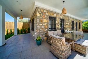 a patio with a table and chairs and a stone wall at Lemon Villa Fethiye in Kayakoy