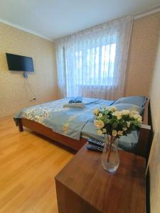 um quarto com uma cama e um vaso de flores sobre uma mesa em 1 комнатные апартаменты на Ауэльбекова 138 em Kokshetau