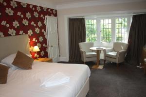 ボーンマスにあるEast Cliff Cottage Hotelのベッド、テーブル、椅子が備わるホテルルームです。
