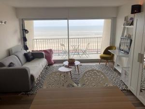 a living room with a couch and a large window at Le nid de la plage in Le Touquet-Paris-Plage