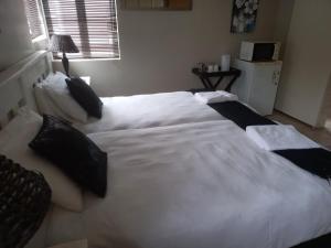 a bedroom with two beds with white sheets and black pillows at Madiolyn in Jeffreys Bay