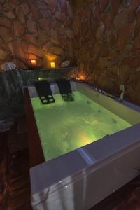 a bath tub filled with green water next to a stone wall at Onore dell'amore 2 in Banja Koviljača