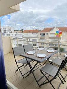 een tafel en stoelen op een balkon met uitzicht op een gebouw bij Le Soleil Levant in Les Sables-dʼOlonne