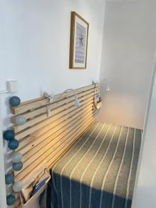 een bed met een houten hoofdeinde in een kamer bij Le Soleil Levant in Les Sables-dʼOlonne