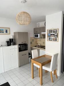 een keuken met een houten tafel en witte stoelen bij Le Soleil Levant in Les Sables-dʼOlonne