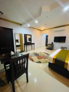 1 dormitorio con cama, escritorio y piano en Arrawiya Alzahabia Hotel, en Dammam