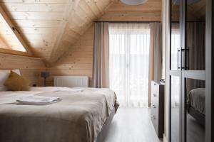 um quarto com uma cama grande e uma janela em Osada Chłabówka Zakopane & SPA em Zakopane