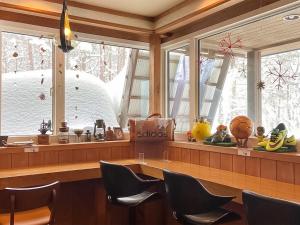 a dining room with chairs and windows with snow at Pension Razteca in Hakuba
