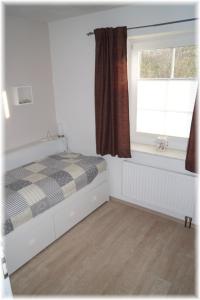 a small bedroom with a bed and a window at Haus Wattenblick EG in Morsum