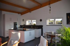 a kitchen with white cabinets and a table and chairs at Un espace au bord de l'eau in Paliseul