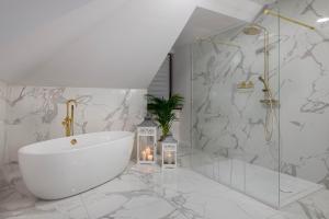 Łazienka z białą wanną i marmurowymi ścianami w obiekcie Hotel Nowodwory w mieście Ciechanowiec