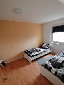 two beds in a room with a window at schöne Ferienwohnung über den Dächern von Plauen in Plauen